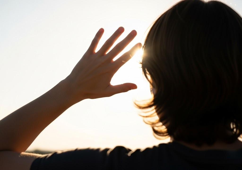 Woman shielding self from sun, after neck and armpit skin tag removal