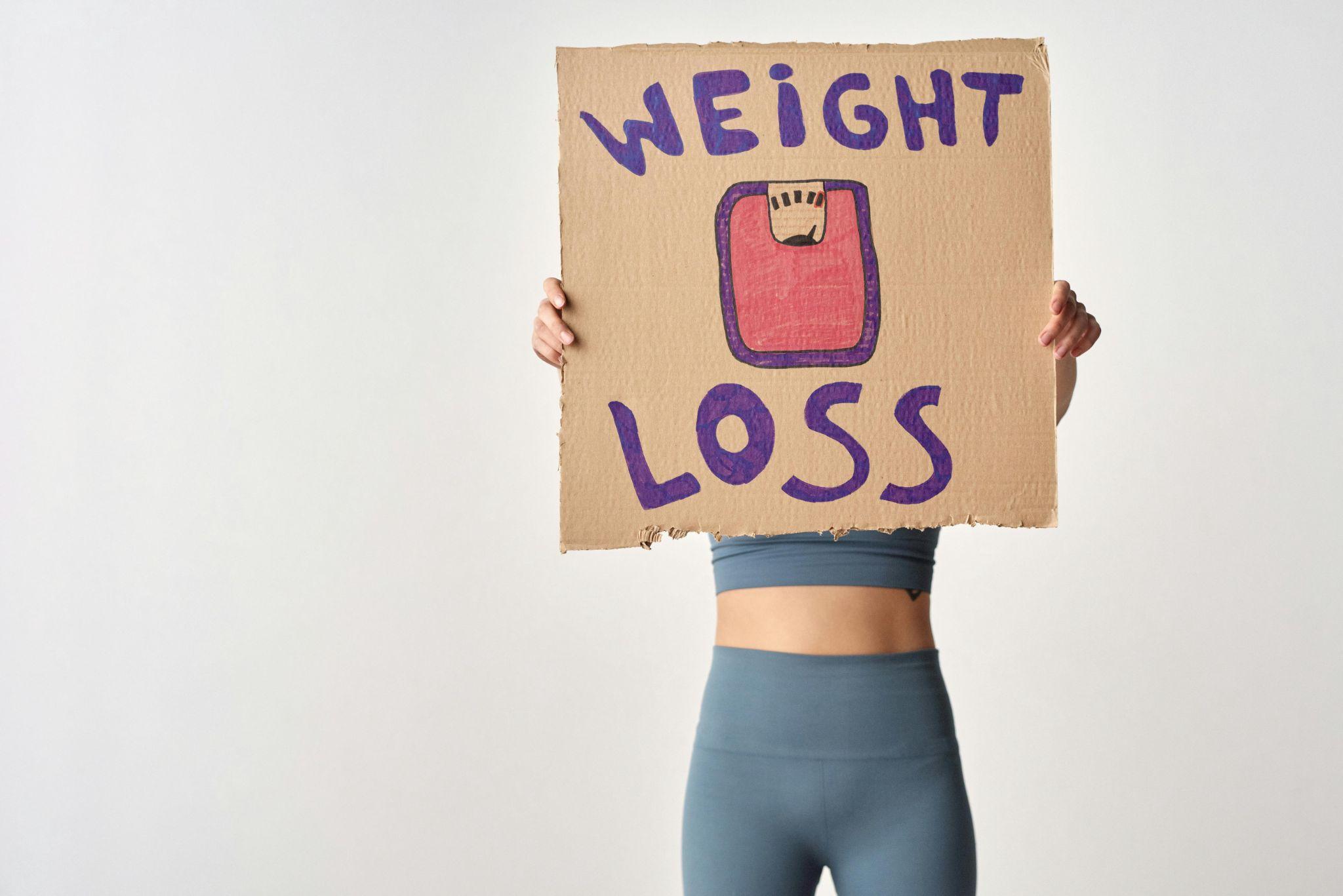 Woman holding up weight loss sign