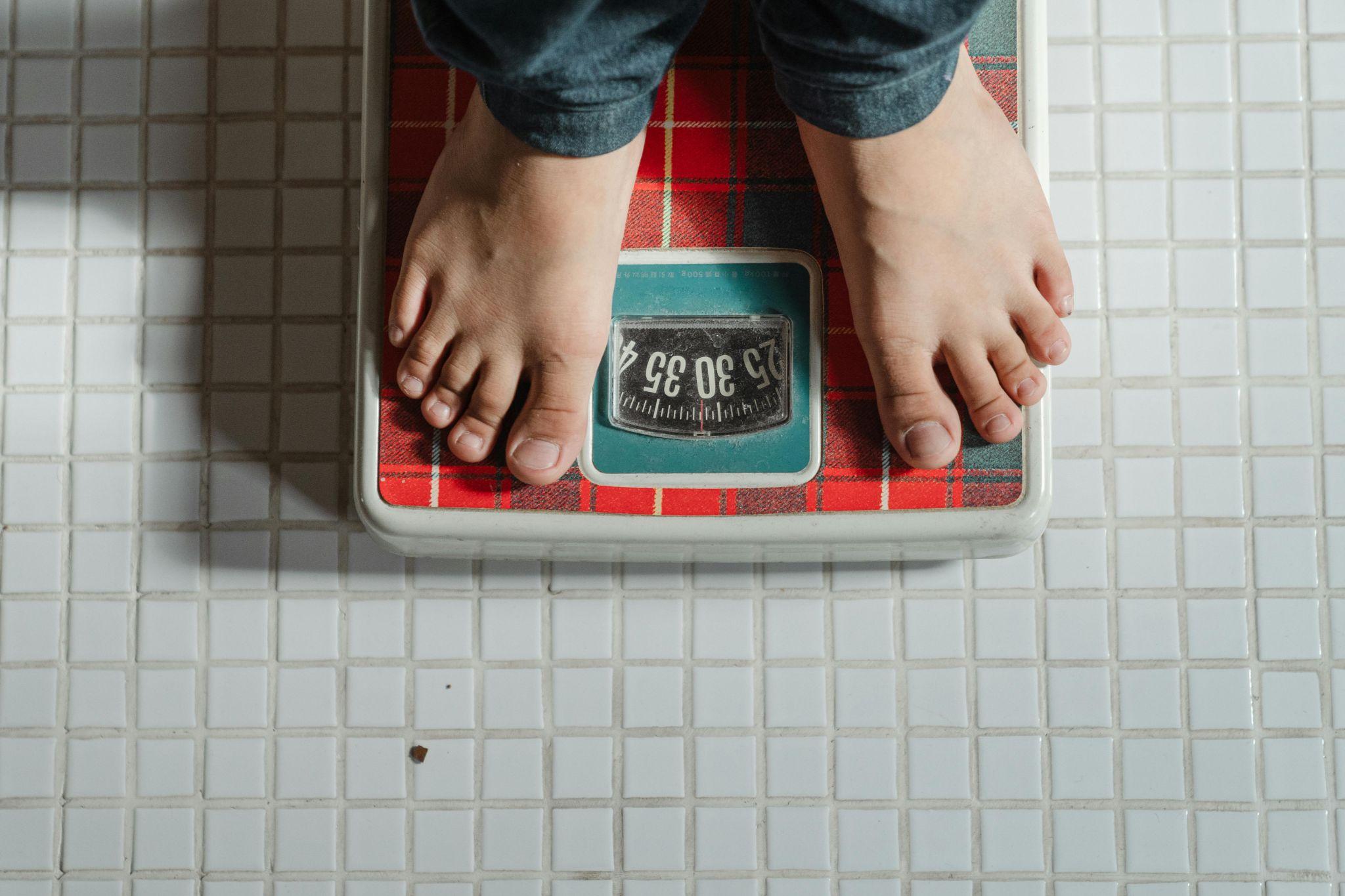 person weighing self on bathroom scale