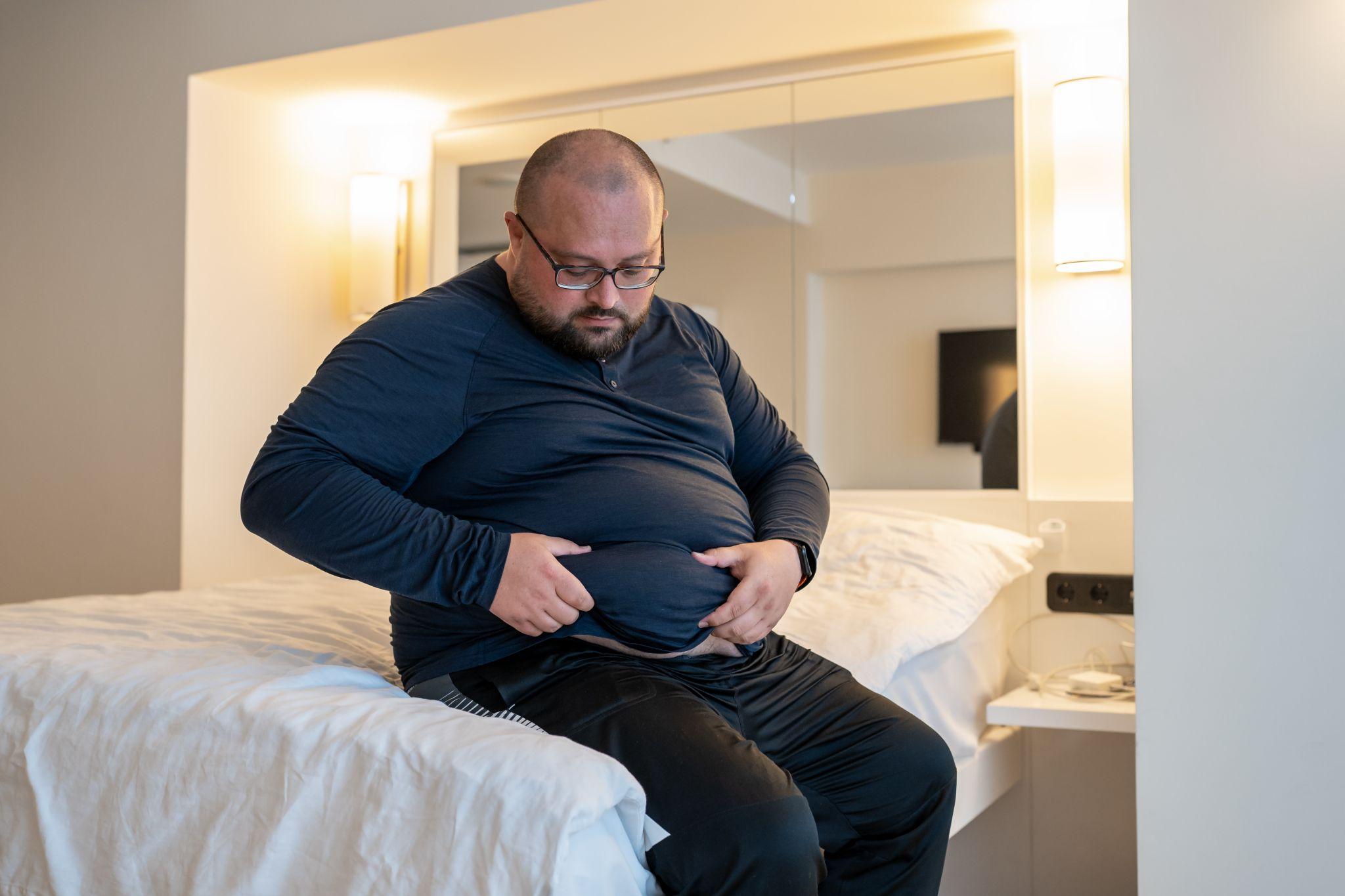 man touching abdomen while considering belly fat burning laser