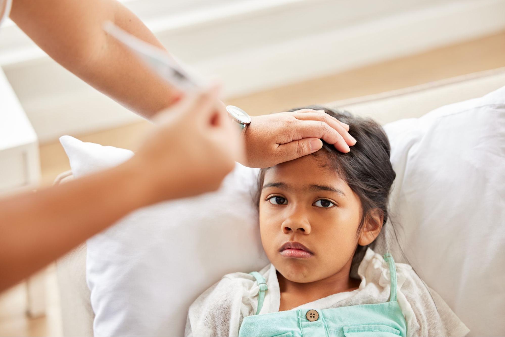 relationship-based primary care showing doctor checking young patient’s temperature