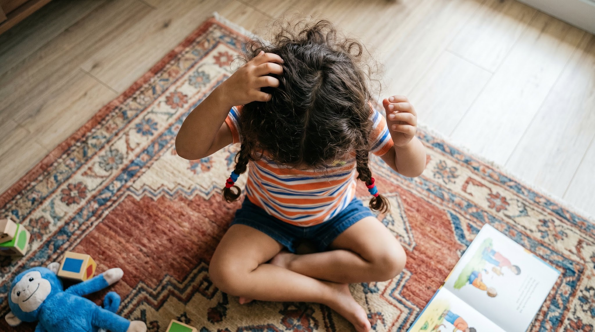 A young child with curly hair scratching scalp