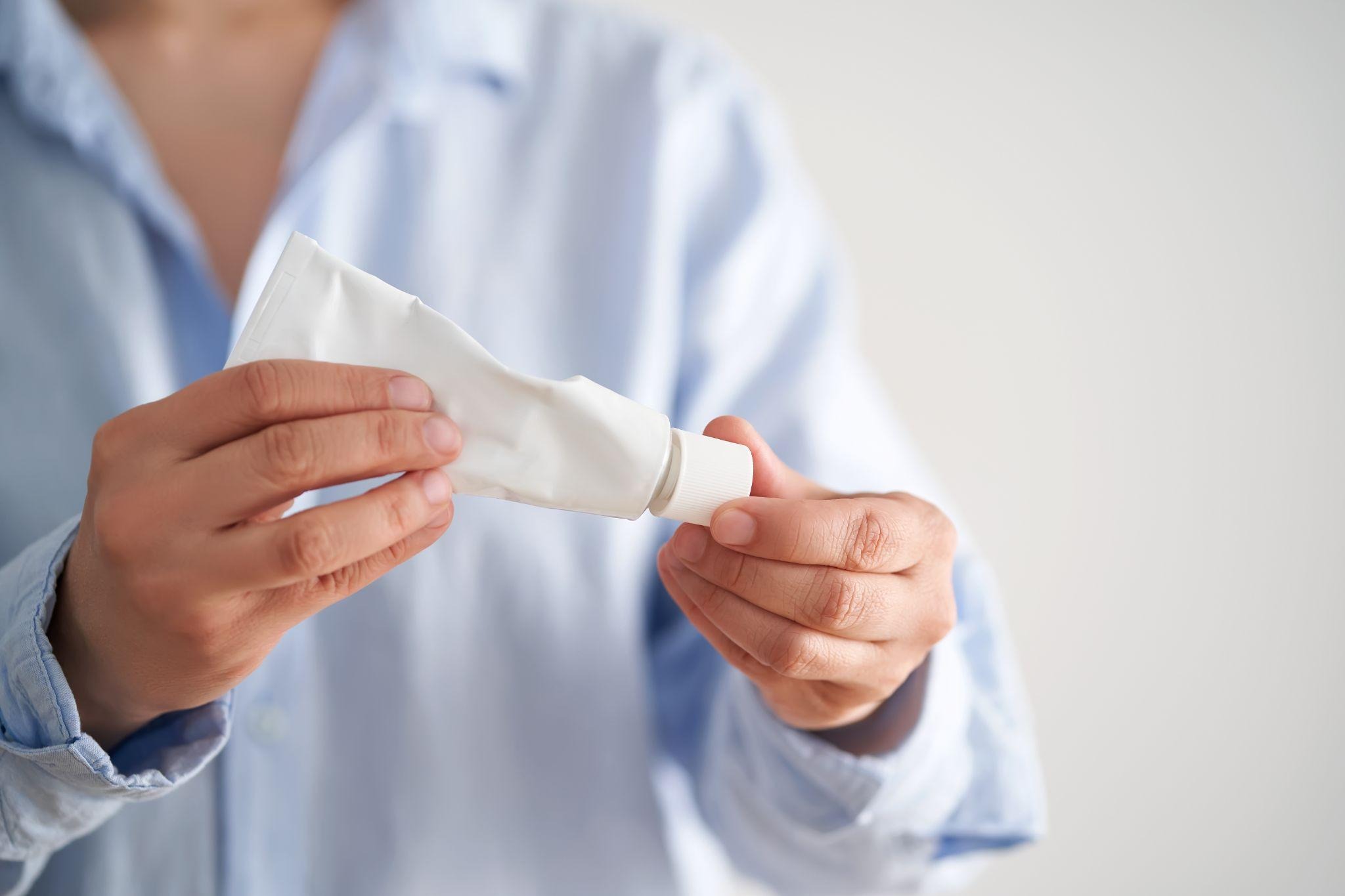 Person holding a tube of topical cream commonly used as part of scabies mite treatment.