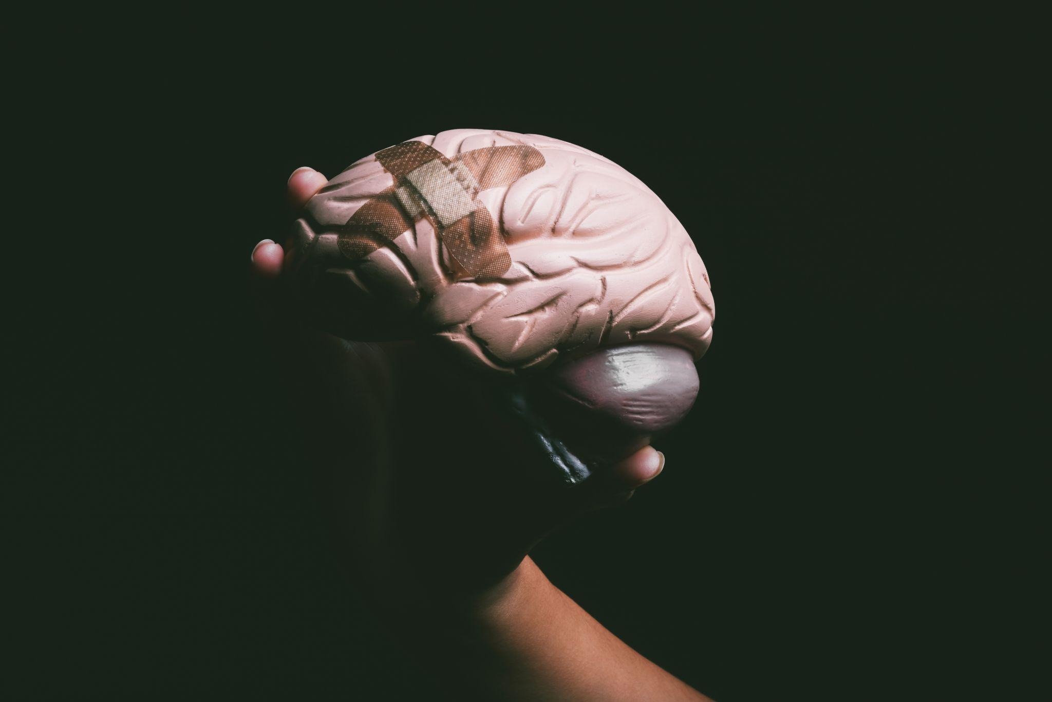 Hand holding a brain model with bandages, representing brain health and recovery related to ketamine for mental health treatment.