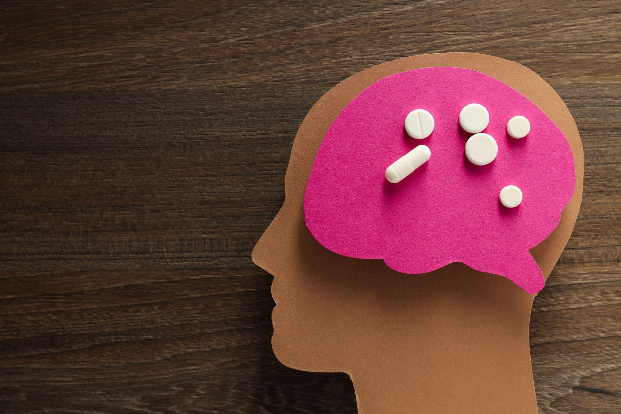 Paper head and brain cutout with medication, illustrating brain health and ketamine for mental health treatment.