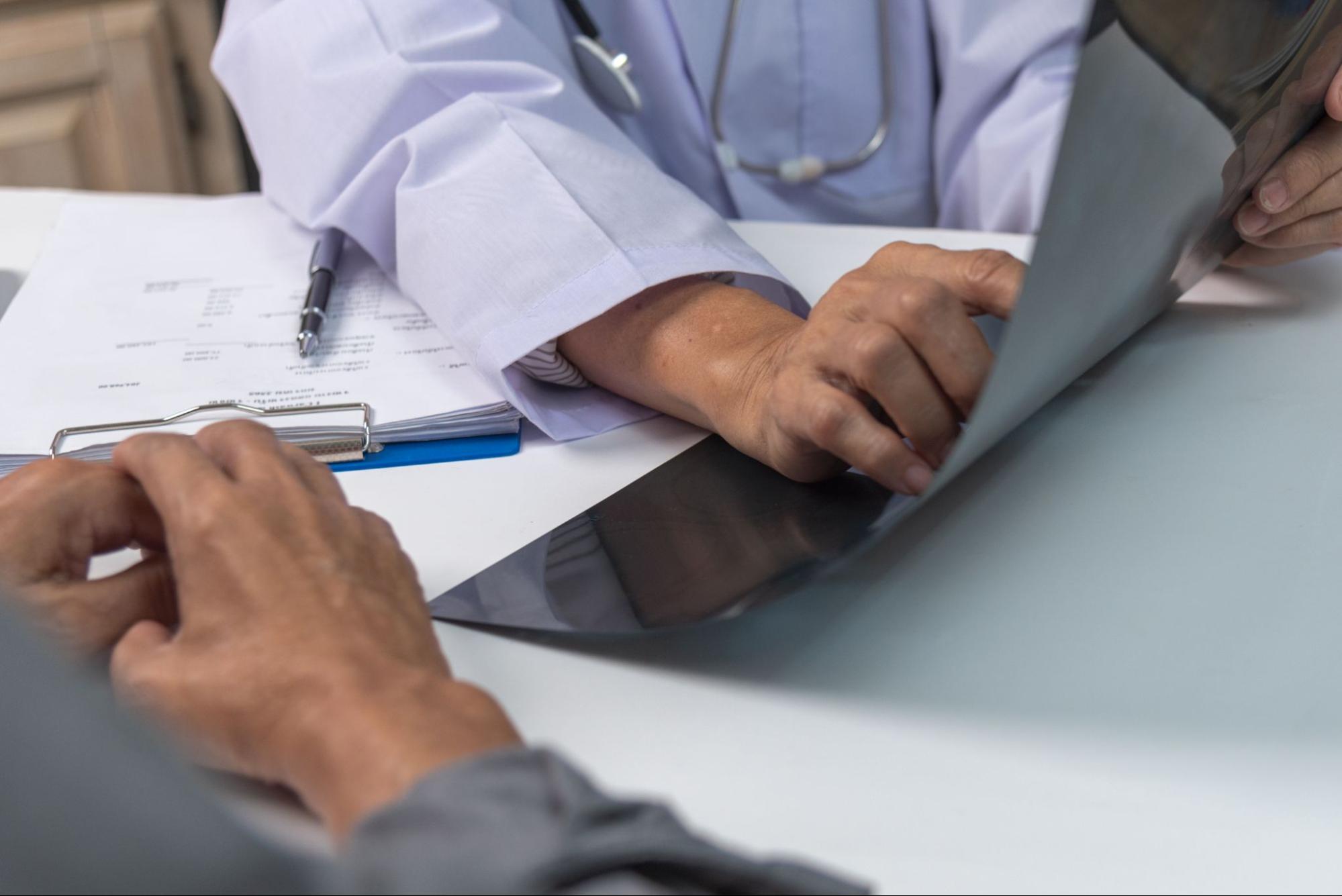 Doctor reviewing medical information on a tablet during a patient consultation.
