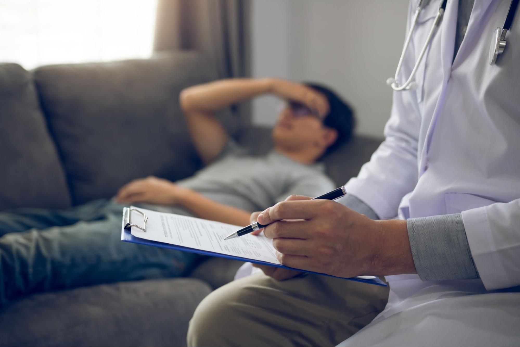 Patient speaking with a medical professional in a clinical setting during supervised mental health treatment.