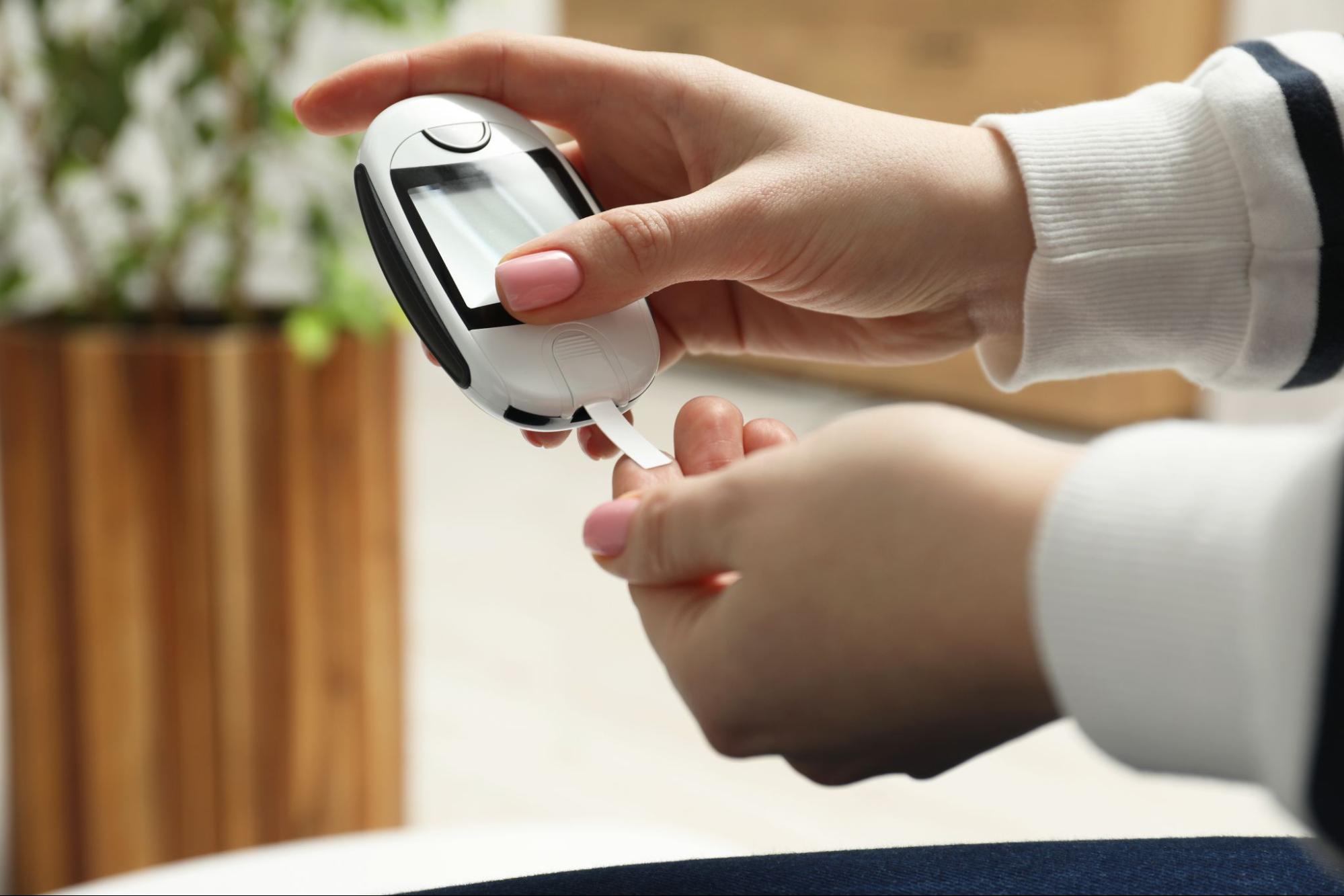 Woman checking her blood sugar level with a glucose meter at home.