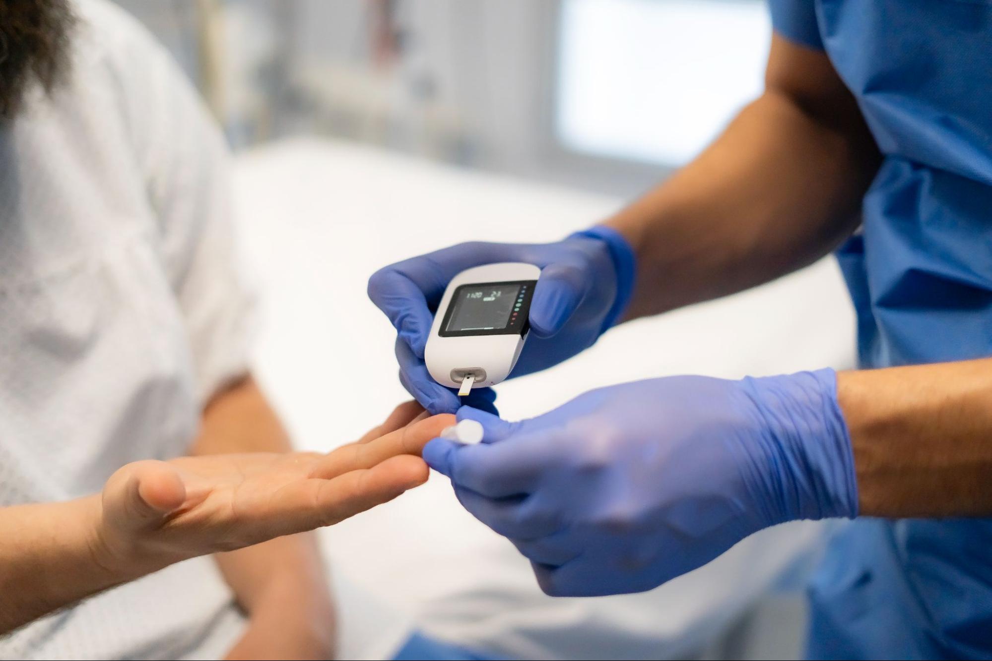 Healthcare professional checking a patient's blood sugar during a medical visit.