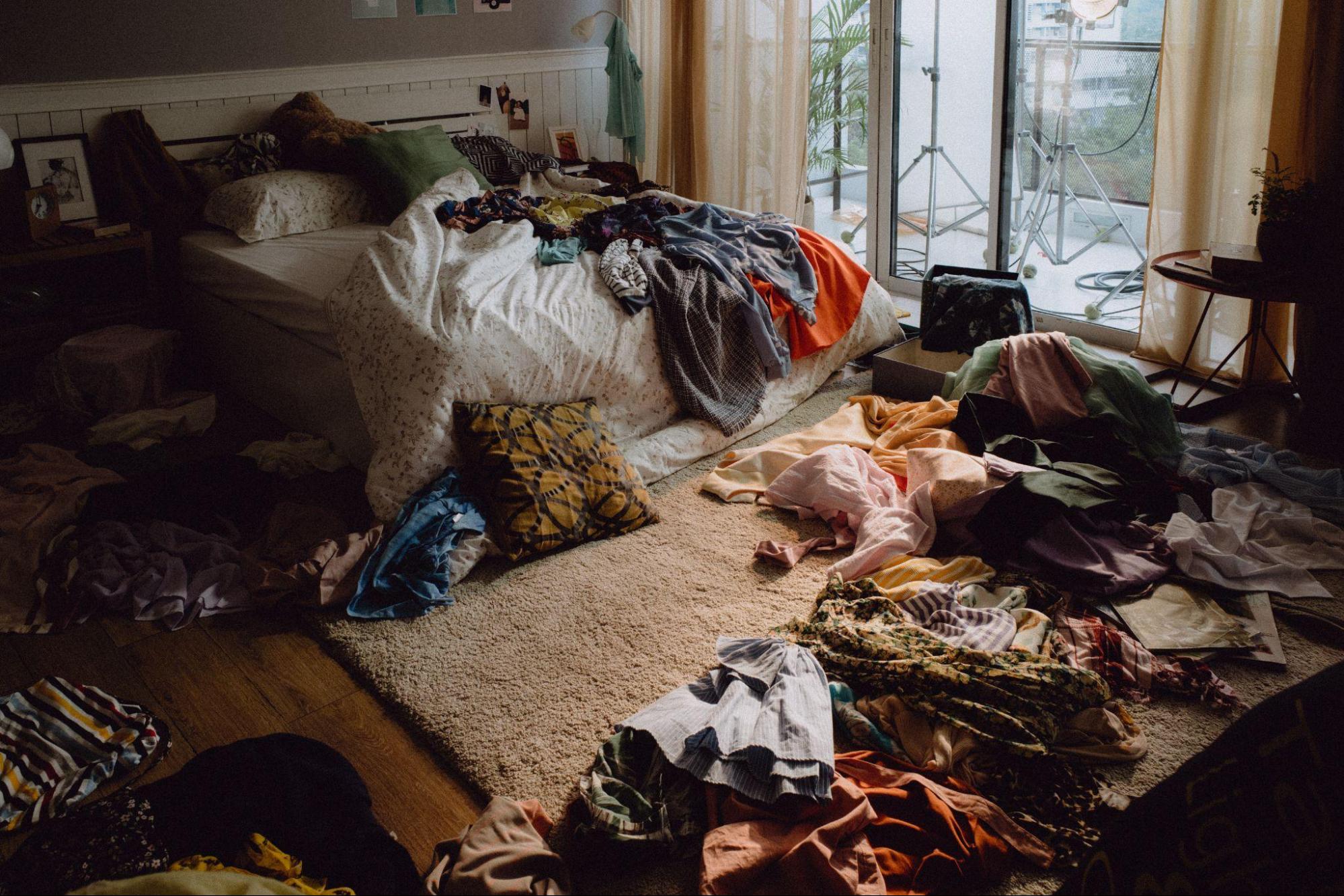 Bedroom with clothing and bedding scattered around, highlighting household items that may need cleaning during scabies treatment for family members.