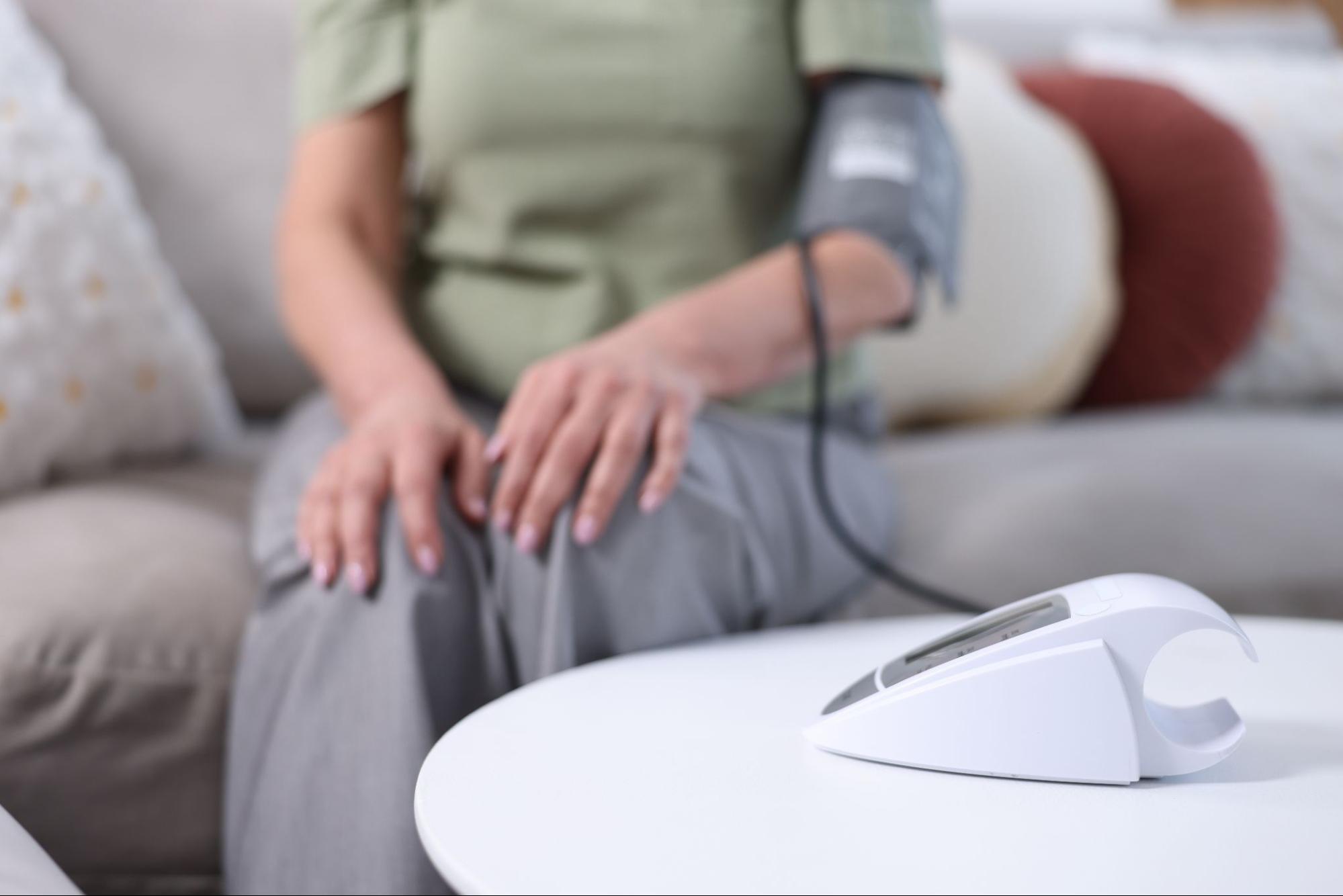 Woman monitoring her blood pressure at home using a digital device.